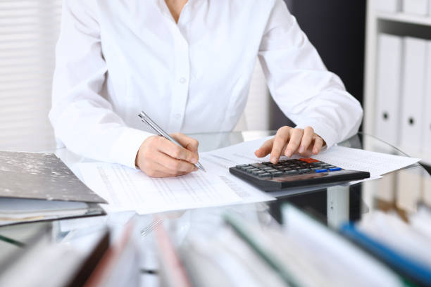 istock Female bookkeeper or financial inspector  making report, calculating or checking balance. Internal Revenue Service checking financial document. Audit concept in busines 946450940