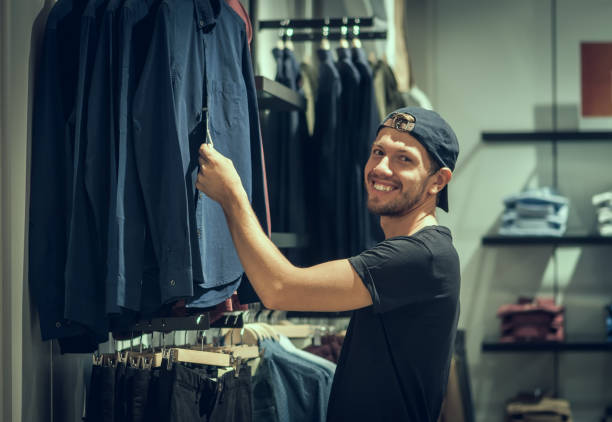 istock Young man choosing clothes in shopping mall 946459320