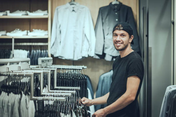 istock Young man choosing clothes in shopping mall 946459344