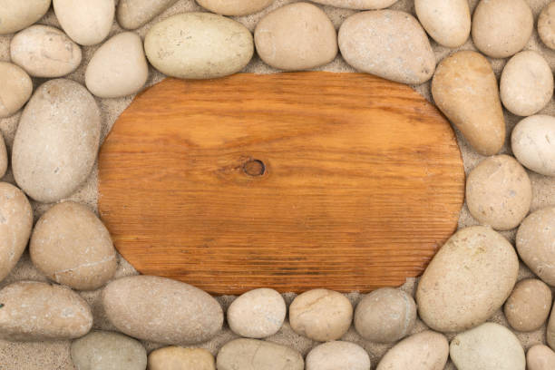 Empty frame of light wood and white stones in the sand. Copy space. Top view