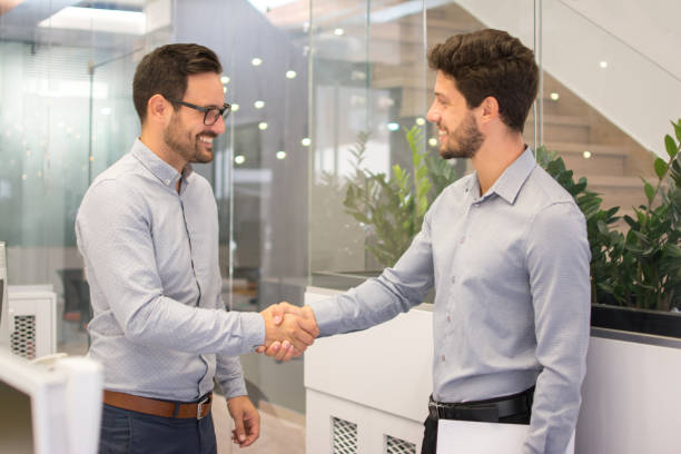 istock Two smiling businessmen shaking hands together in office 946483332