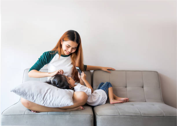 istock Asian kids using smartphone sitting together on sofa 946486384
