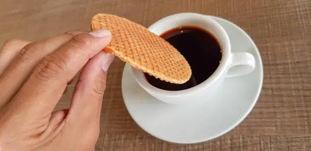 Photo of Stroopwafel a famous waffle from dutch dip into the black coffee.