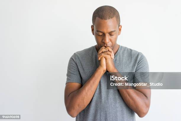 Calm Spiritual Handsome African Guy Praying With Closed Eyes Stock Photo - Download Image Now