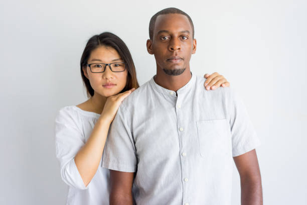 calm beautiful young interracial couple looking at camera - couple young adult african descent multi ethnic group imagens e fotografias de stock