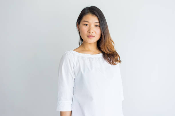 Serious beautiful young Chinese woman in white blouse Serious beautiful young Chinese woman in white blouse looking at camera. Portrait of calm confident girl with beautiful hair. Lady concept chinese woman stock pictures, royalty-free photos & images