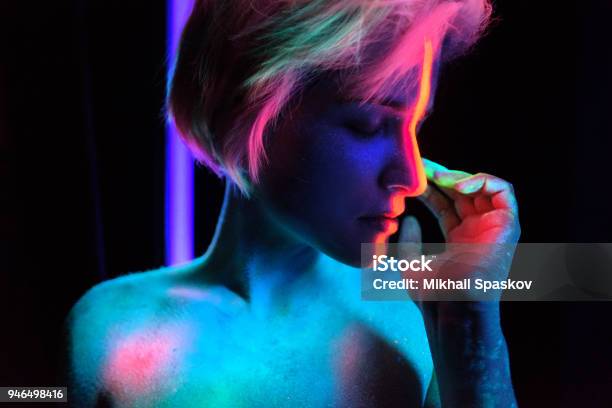 Model Young Beautiful Girl Portrait In Studio With Creative Makeup In Neon Ultraviolet Lamp Glows In The Dark Hair Coloring With Neon Paints Body Art Is Blue Green Orange Stock Photo - Download Image Now