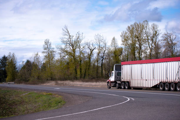 istock Big rig day cab semi truck transporting covered bulk semi trailer with commercial cargo 946503152