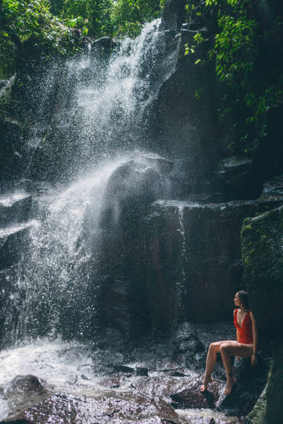 istock Woman standing  under  waterfall in Bali, Indonesia 946519624