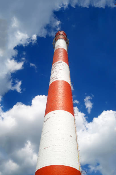 Red-white chimney of a large plant. Bottom view. On the blue sky background. Red-white chimney of a large plant. Bottom view. On the blue sky background. chicago smog stock pictures, royalty-free photos & images