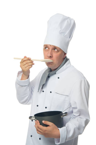 istock cook, on white background, holds a pan in his hand and tries a dish 946531478