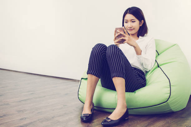 istock Smiling woman sitting on beanbag reading message 946533204