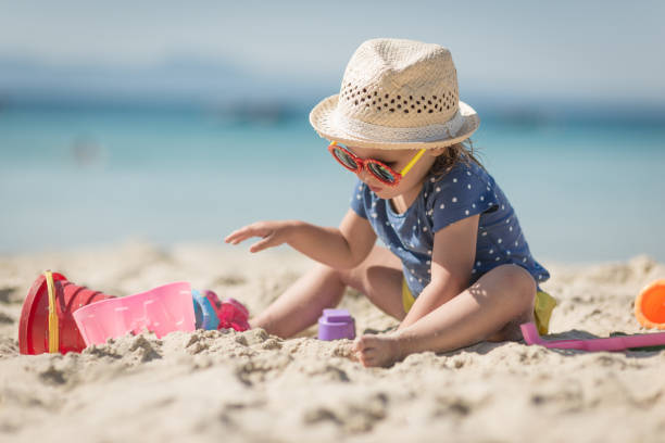 chica de toysle de playa littplayng caucásico con sombrero - child beach playing sun fotografías e imágenes de stock