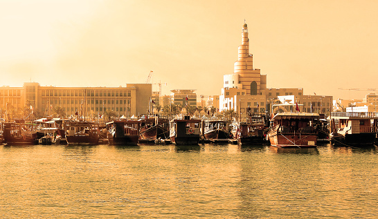 View of embankment with numerous traditional wooden ships in Doha, Qatar at sunset