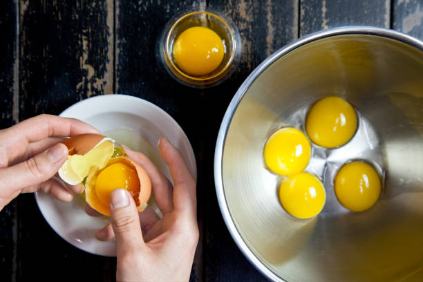 istock Baker cracking eggs in steel bowl. preparing food. baking process 946551954