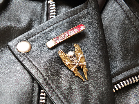 detail of black leather classic biker jacket with metal badges