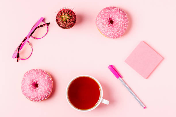 istock Cup of tea with donuts on a pink pastel background 946566876
