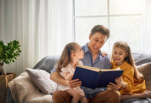 istock father reading a book to his daughters 946566962