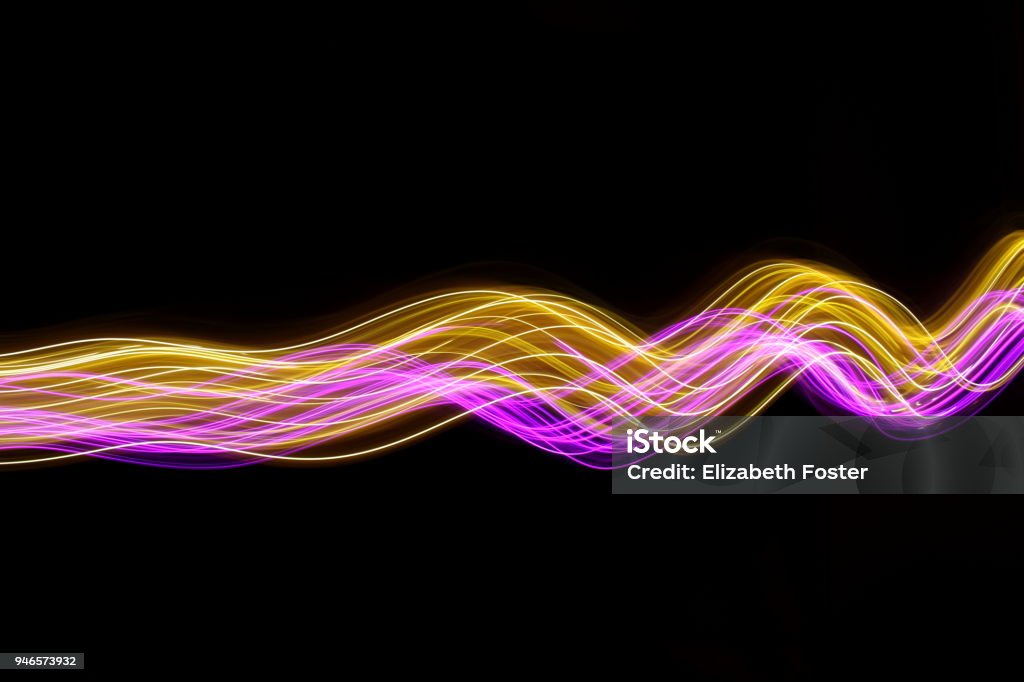 Pink and gold light painting photography, long exposure photo of fairy lights against a black background Long exposure abstract photo of colored fairy lights in swirls and waves Wave Pattern Stock Photo