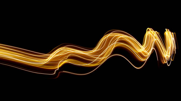 Gold light painting photography, long exposure photo of metallic gold fairy lights in a swirling, curves and waves pattern, against a black background A long exposure photograph of gold fairy lights going horizontally across the frame in a curving, wavy design, against a black background Long Time Exposure stock pictures, royalty-free photos & images