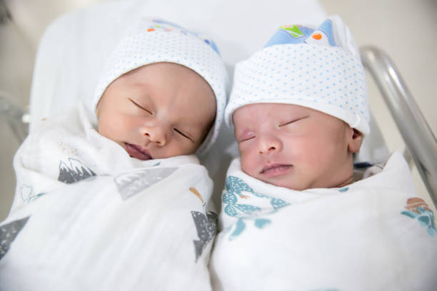 pasgeboren tweeling slapen. pasgeboren baby's tweeling slapen in bed. - eeneiige tweeling stockfoto's en -beelden