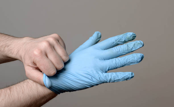 man putting on a pair of latex gloves - nitril imagens e fotografias de stock