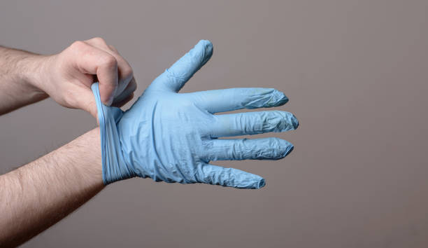 man removes a pair of used latex gloves - nitril imagens e fotografias de stock