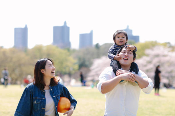 Japanese family having fun in spring A young Japanese family with one child is having fun in a public park during spring in Saitama prefecture. holding child flower april stock pictures, royalty-free photos & images