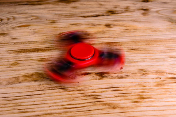istock Red fidget spinner rotates on wooden desk 946607060