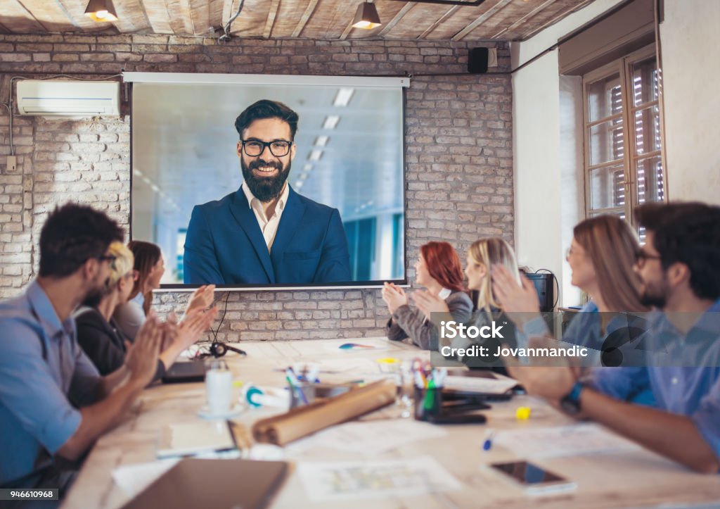 Business people looking at projector during video conference in office Video Conference Stock Photo