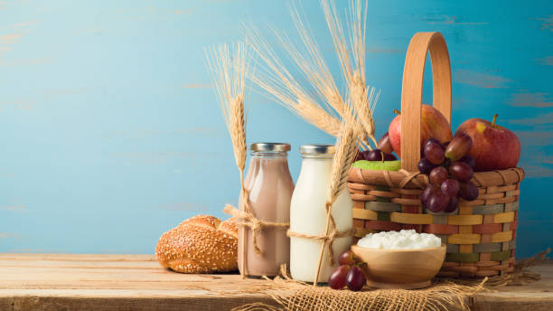 Jewish holiday shavuot concept Milk, chocolate milk bottles and basket with fruits on wooden table. Jewish holiday shavuot concept. grain and cereal products stock pictures, royalty-free photos & images