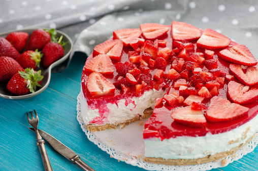 Strawberry summer fresh red fruit and delicious baked homemade dessert cake on blue wooden background