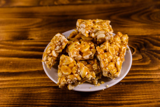 istock Ceramic plate with peanut brittles on wooden table. 946632262
