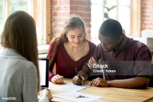 Multiracial Couple Signing Deal From Real Estate Agent Stock Photo - Download Image Now