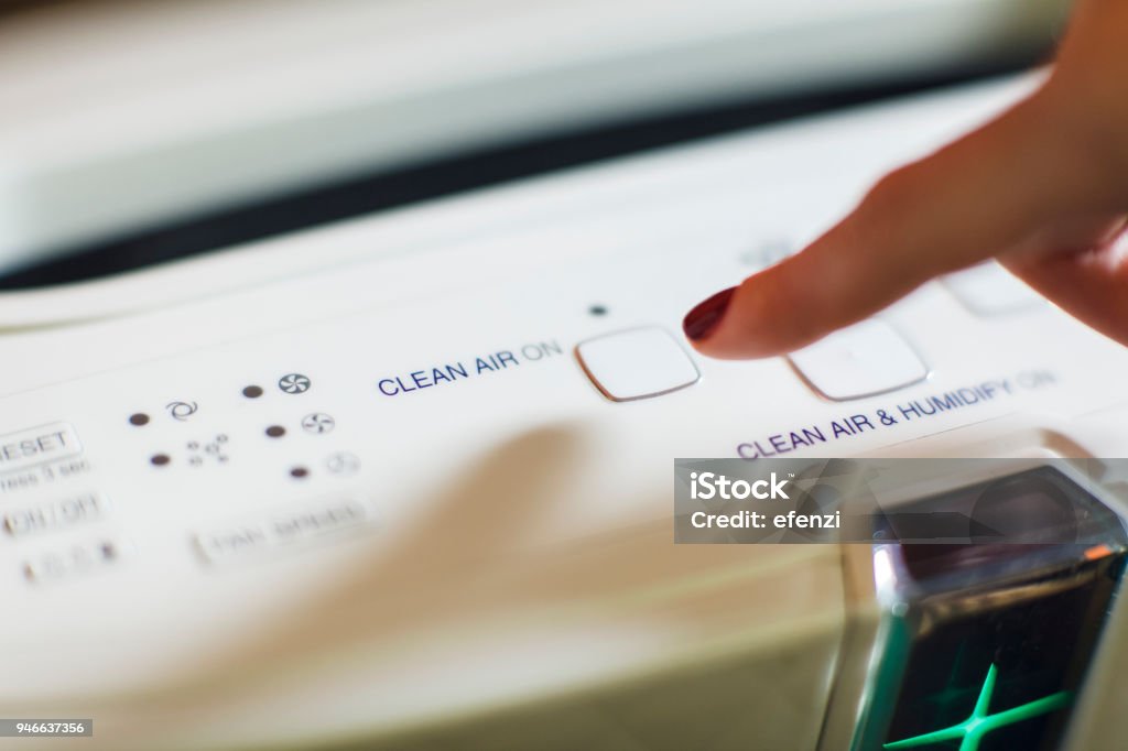 Turning On Modern Air Purifier And Ionizer Close-up of female hand turning on an air purifier and ionizer Wind Stock Photo