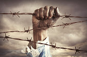 Hand of refugee holding barbed wire
