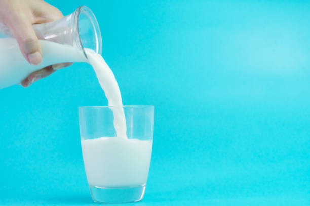 istock Milk poured into a glass on blue background 946647998
