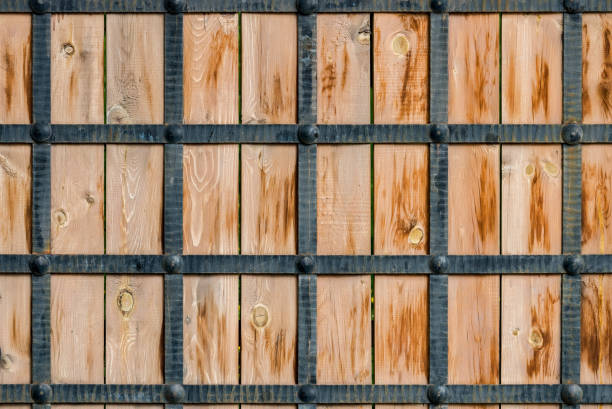 Wooden texture framed by metal forged strips. Stylization of the ancient gate of the castle Wooden texture framed by metal forged strips. Stylization of the ancient gate of the castle. gnarly wood texture stock pictures, royalty-free photos & images