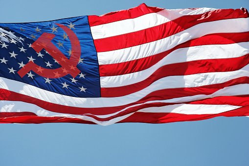 Symbolic Russian hammer and sickle superimposed over United States stars and stripes flag. International political turmoil.