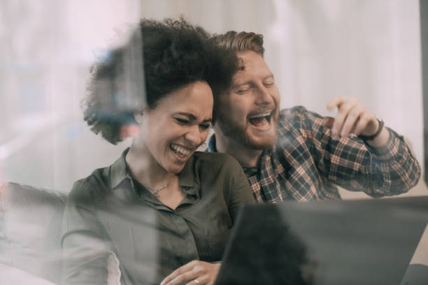 istock Couple laughing out loud while using laptop in coffee shop 946652400