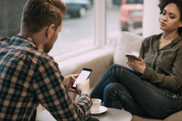 istock Couple using phones in coffee shop 946654488