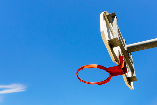 Low angle view of orange basketball hoop against a blue sky