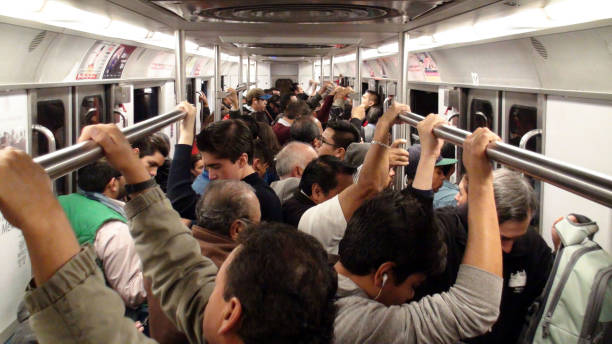 Scenery Of Lots Of People Standing, Looking Around, Listening To Music, Reading Text Message With Smartphone, Holding Hand On Handrail Inside Metro During The Rush Hour In Mexico City Mexico