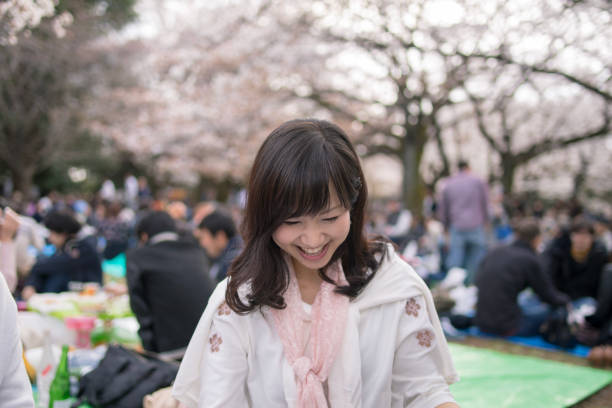 istock Young woman enjoying hanami party under cherry trees 946696082