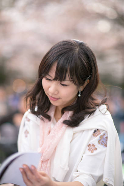 istock Young woman reading book in public park 946696092