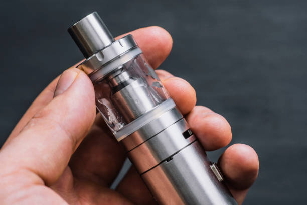 istock man holding electronic cigarette or vape device with smoke at the background. 946705862