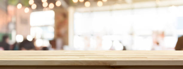 Wood table top on blur restaurant or cafe interior banner background