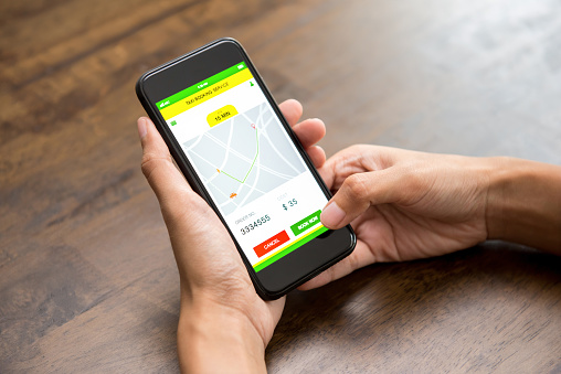 Woman hand touching smartphone screen confirming taxi booking online via application, after checking price and location on digital map