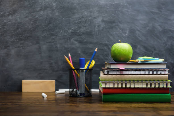 książki, artykuły papiernicze i materiały edukacyjne na drewnianym biurku w klasie - back to school blackboard education apple zdjęcia i obrazy z banku zdjęć