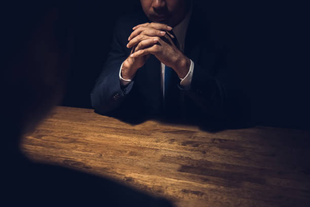 Detective interviewing suspect in dark private room Detective interviewing suspect in dark private room - investigation and interrogation concepts suspicion stock pictures, royalty-free photos & images